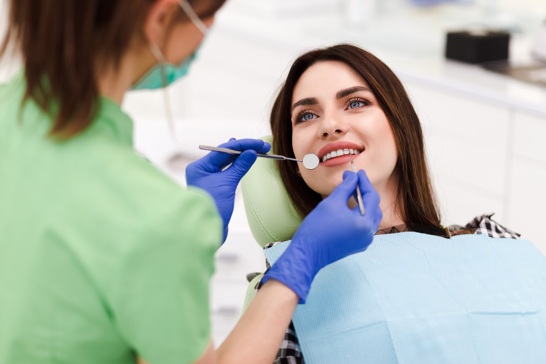 Beautiful young woman doing tooth examination in the dental office.  Portrait of smiling girl on a dental chair in dentistry