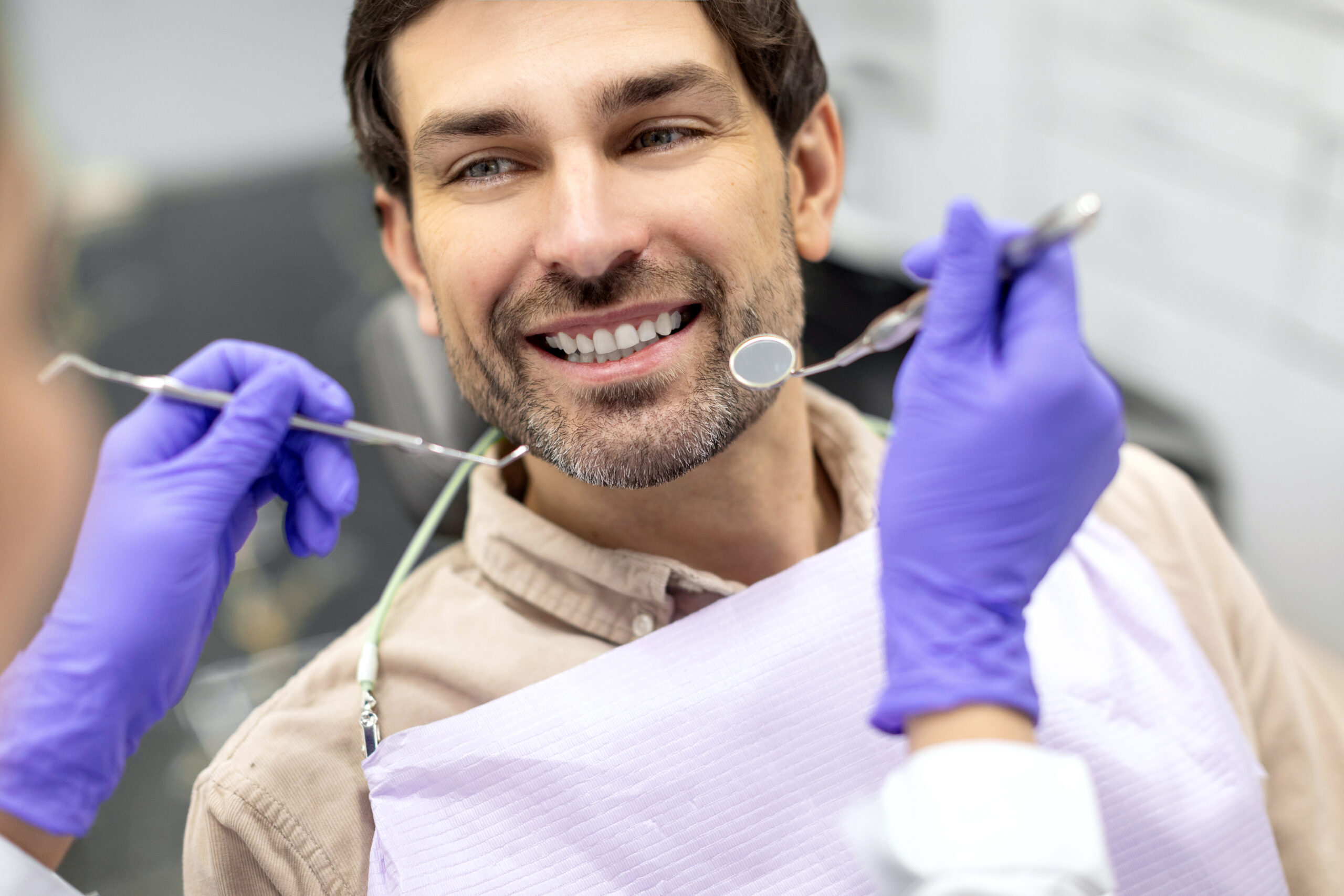 Closeup shot of dentist examining male patients teeth in dental clinic. Man having his teeth examined by female dentist