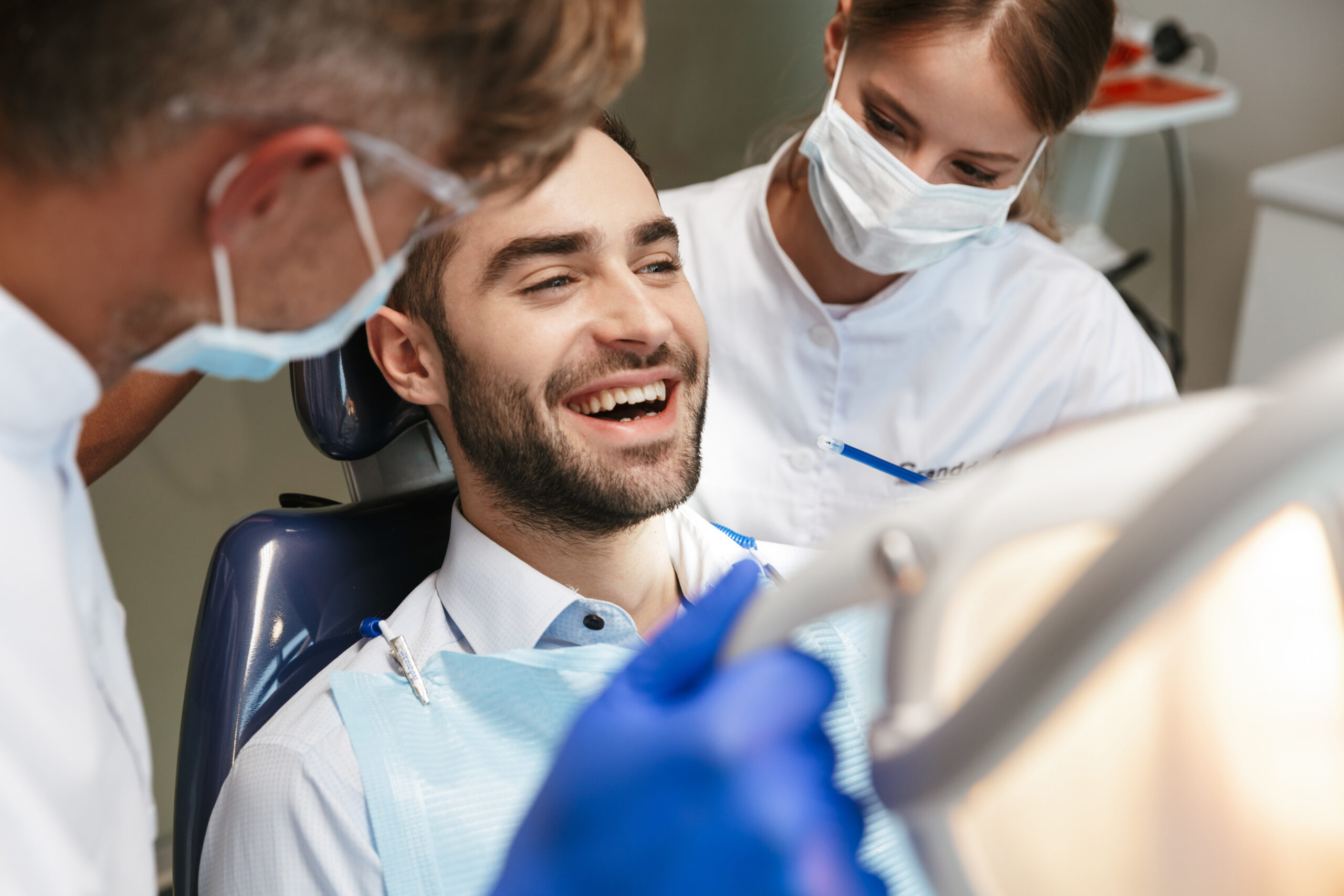 Image of a handsome happy young man sitting in medical dentist center.