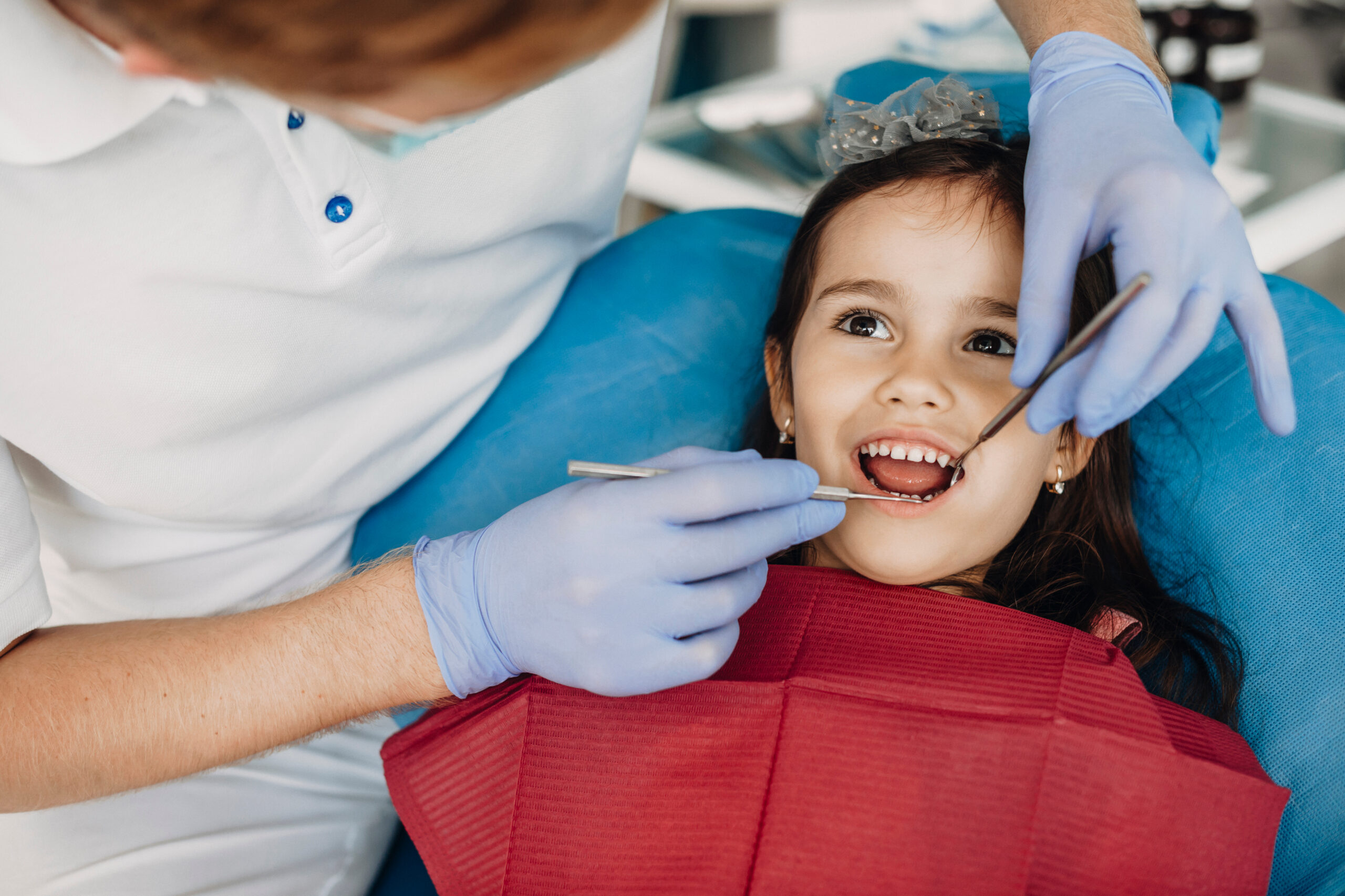 Pediatric dentist checking a young child's teeth during a dental visit